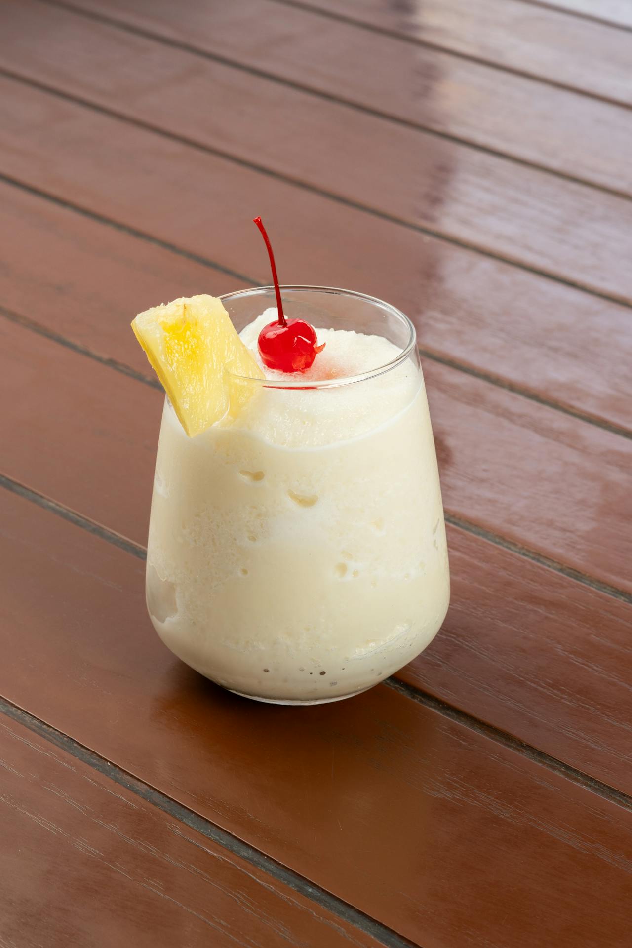 <p>In a shaker, combine pineapple juice and coconut cream, shaking well to mix.</p> <p>Fill a glass with ice and pour the pineapple-coconut mixture over the ice.</p> <p>Top with club soda for a bubbly finish.</p> <p>Garnish with a pineapple wedge and a maraschino cherry.</p> :: Pexels